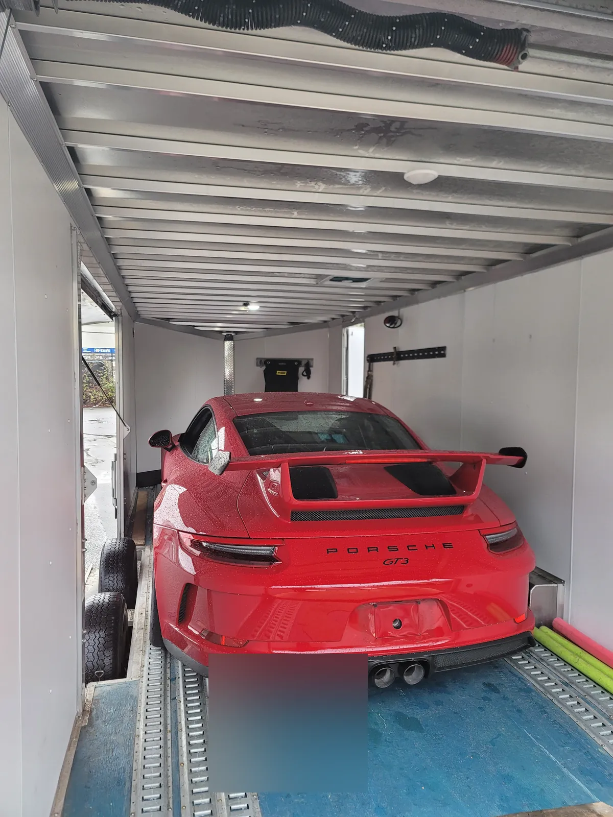 Red Porsche 911 GT3 secured inside an enclosed auto transport trailer.