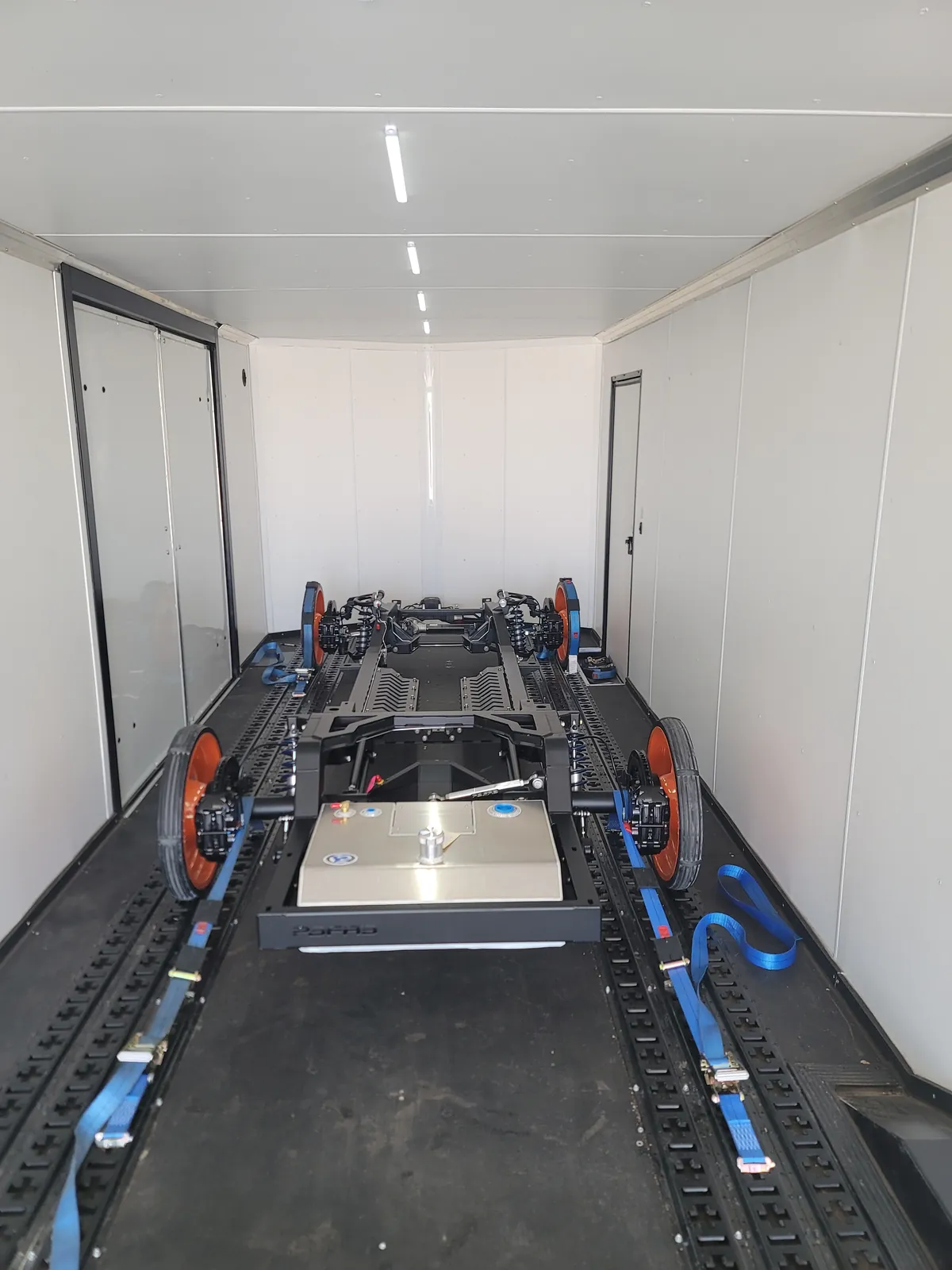 Empty enclosed trailer showing the wheel-net and soft-strap tie-down system.